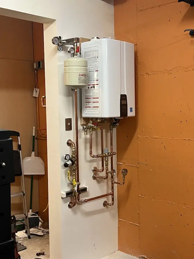 Plumbing technician inspecting water heater connections in Hartland